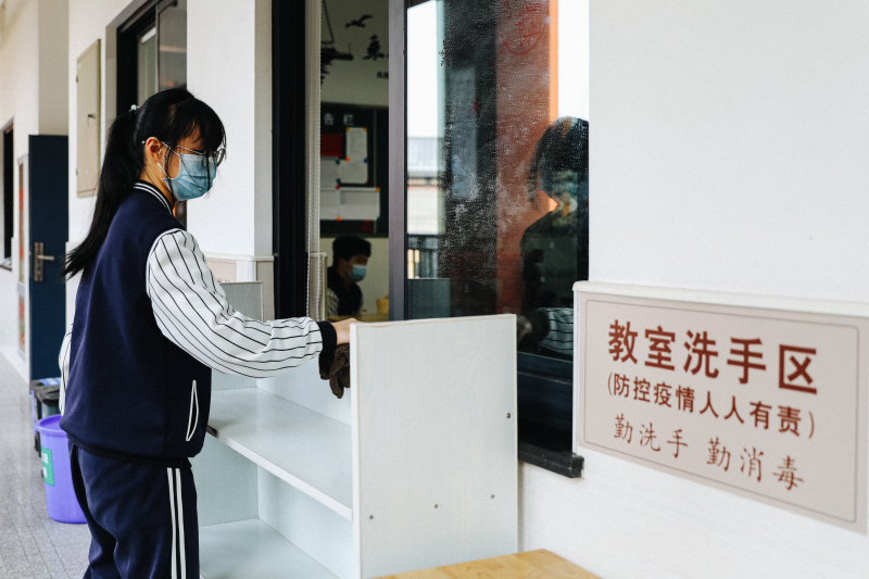 余姚疫情后开学学生戴口罩排队测温上学打扫