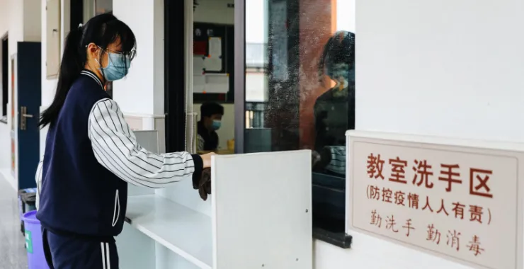 余姚疫情后开学学生戴口罩排队测温上学打扫